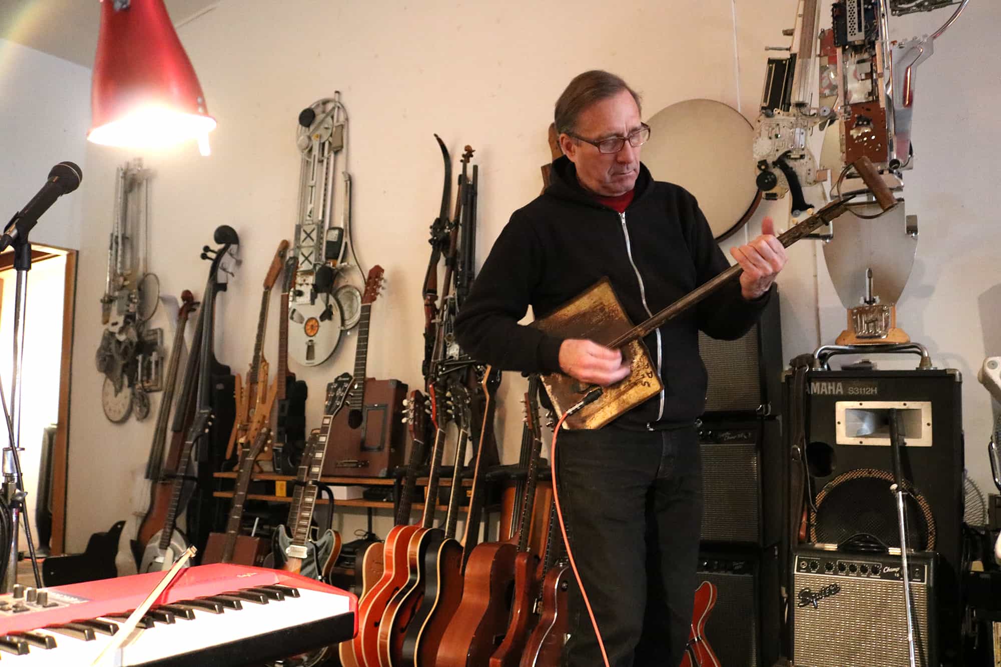 Ken Butler jamming on a shovel guitar in his studio. Photo: Megan Penmann