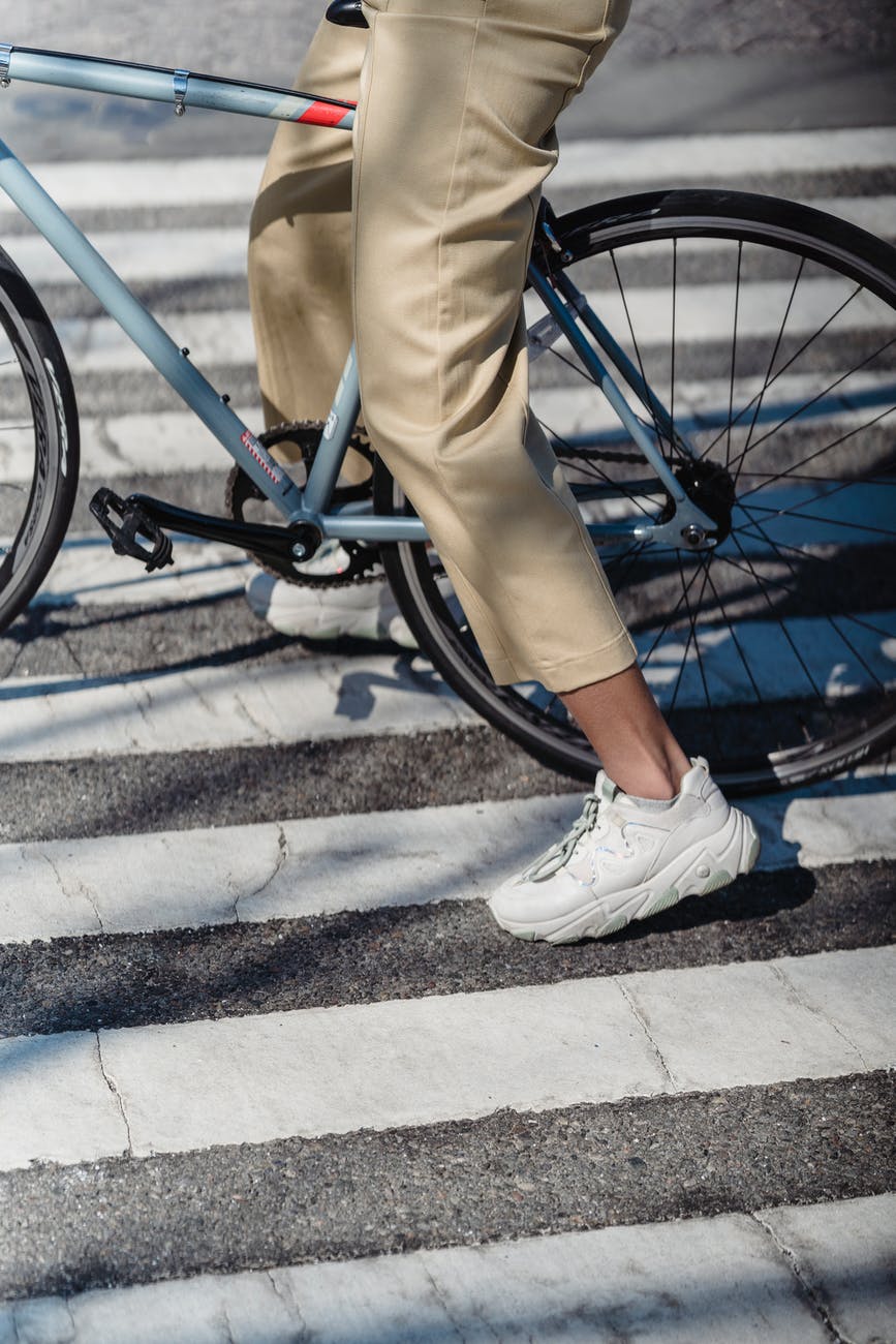 unrecognizable woman riding bicycle on crosswalk
