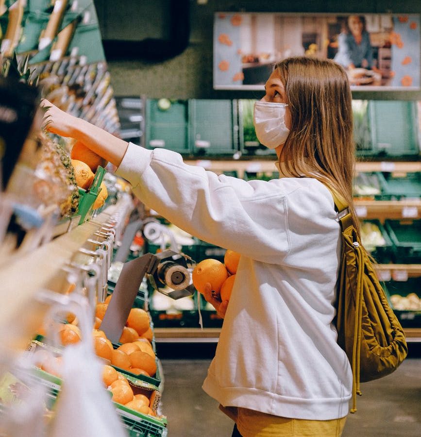 woman in white long sleeve jacket shopping for fruits